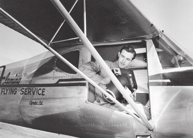 Screen image of Shuster and his camera in his plane.